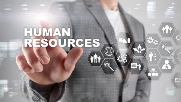 A professional in a suit pressing a glowing virtual touchscreen with the words "HUMAN RESOURCES" next to modern HR icons including recruitment, teamwork, and analytics.